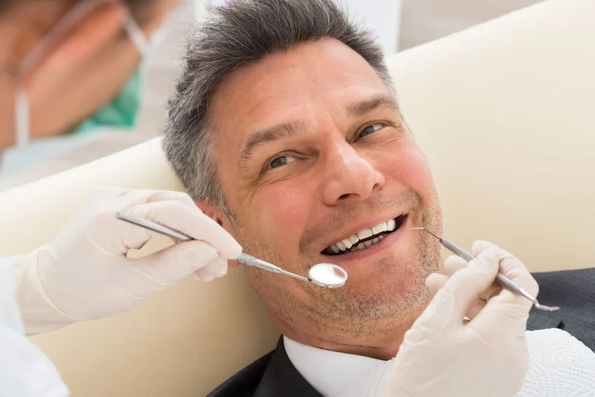 Man looking up at dental assistant, smiling